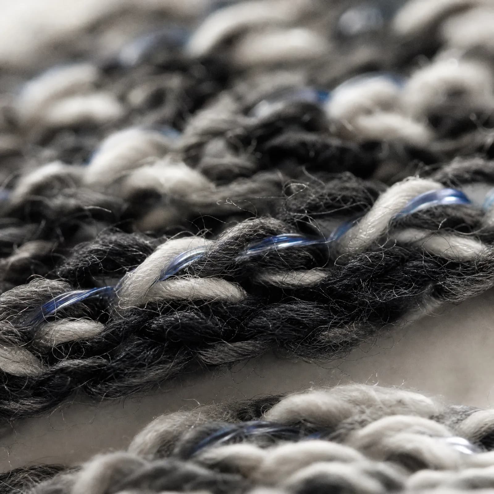 Extreme macro of knitted cotton yarn with a fine translucent elastic filament plied through it.