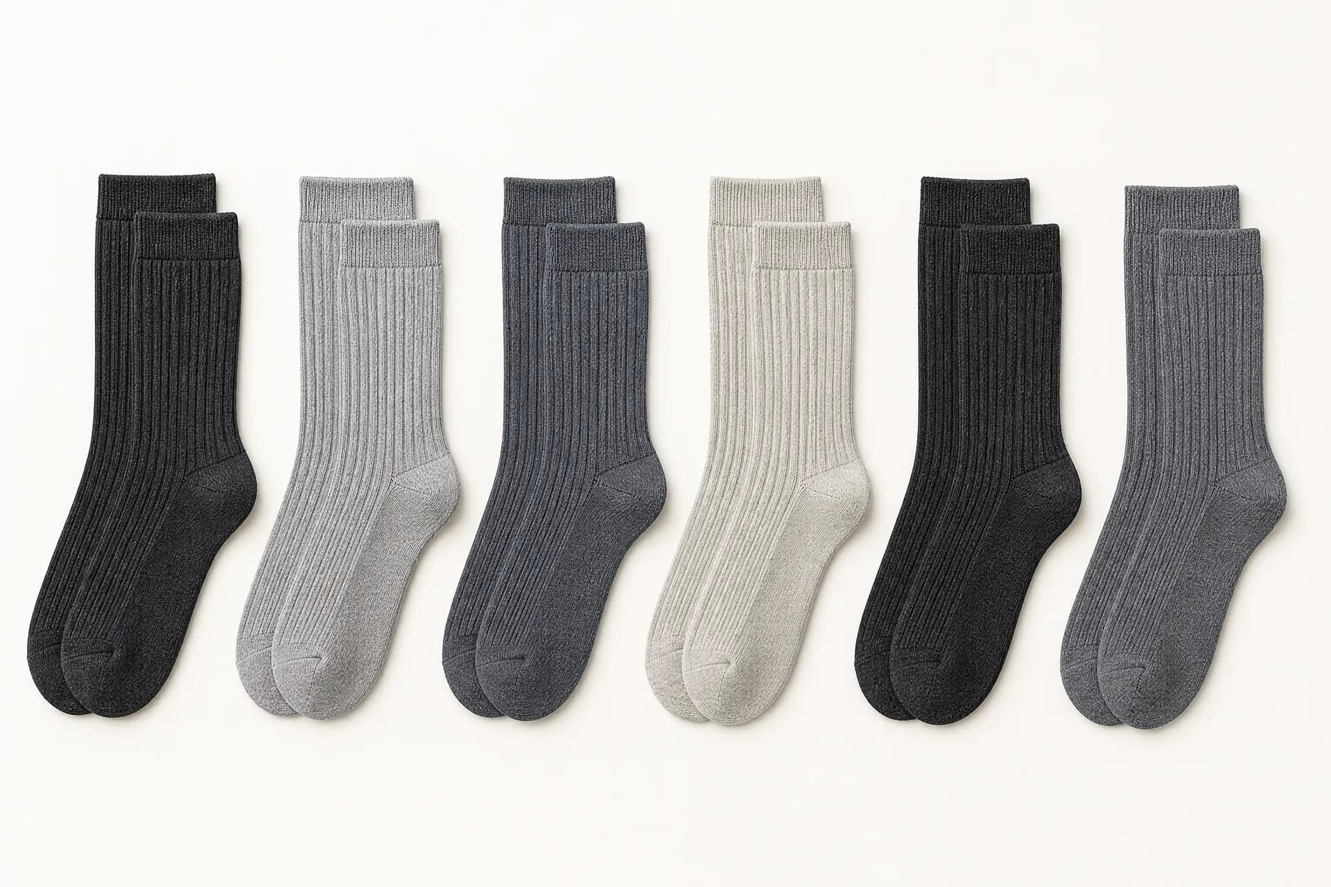 Six pairs of ribbed socks laid perfectly flat in a row, cuffs aligned along a single line.