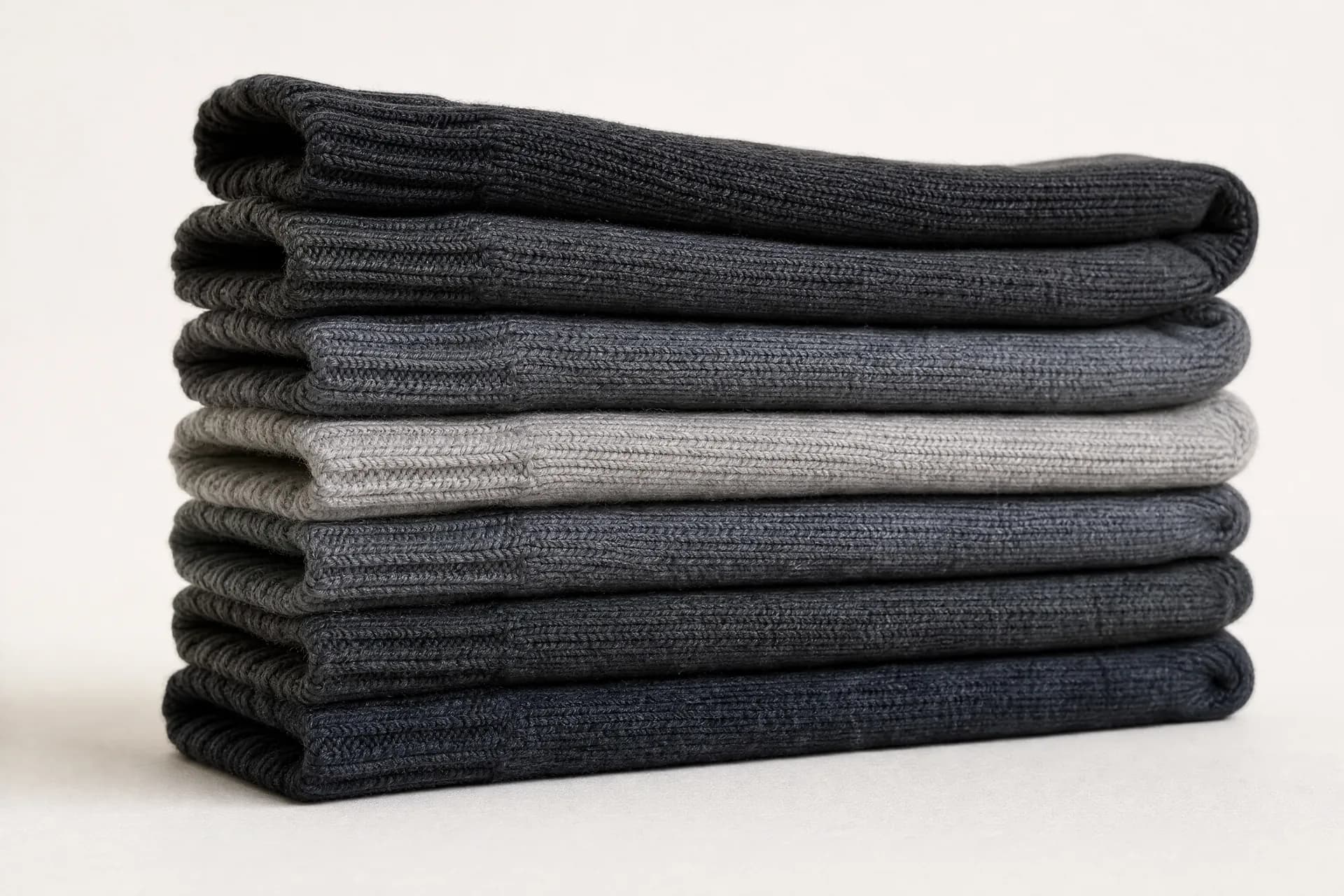 A low stack of about eight folded thick ribbed winter socks seen from the side, the folded edges reading as stacked bands.
