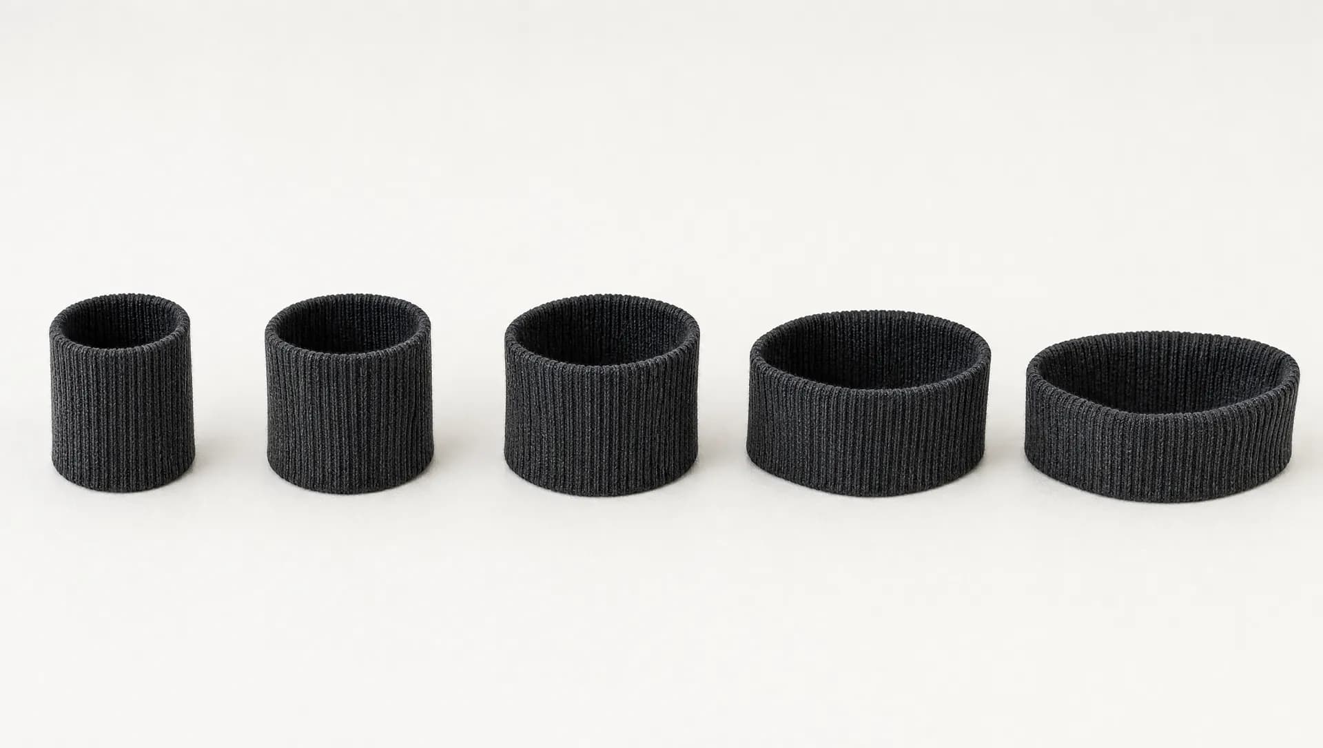 Five identical graphite ribbed sock cuffs in a row, each progressively wider and slacker from left to right.
