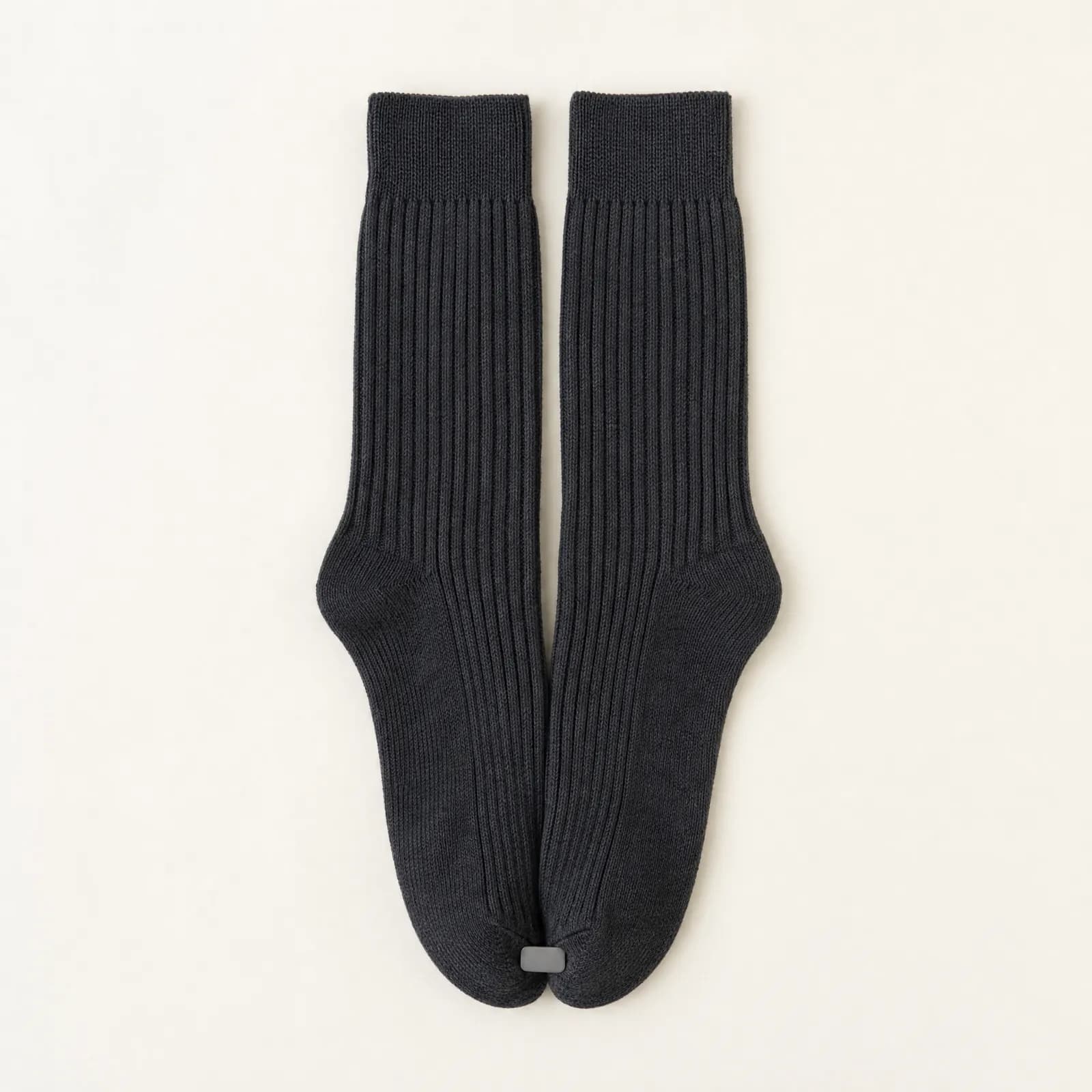 A pair of graphite ribbed socks laid flat side by side, joined near the toe end, both cuffs lying relaxed.