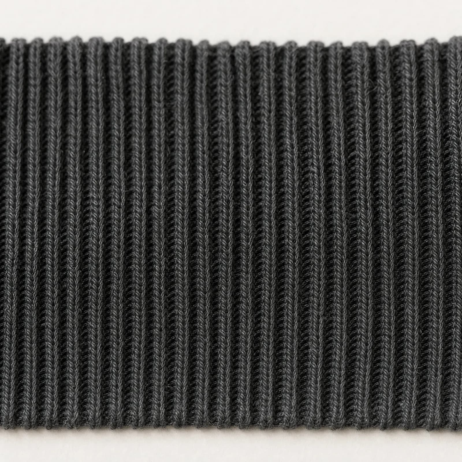 Macro swatch of a fine 1 by 1 ribbed knit cuff in graphite cotton.